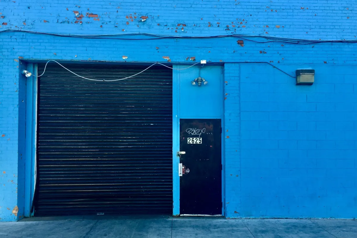 Black roll-up door and service door on a bright blue building